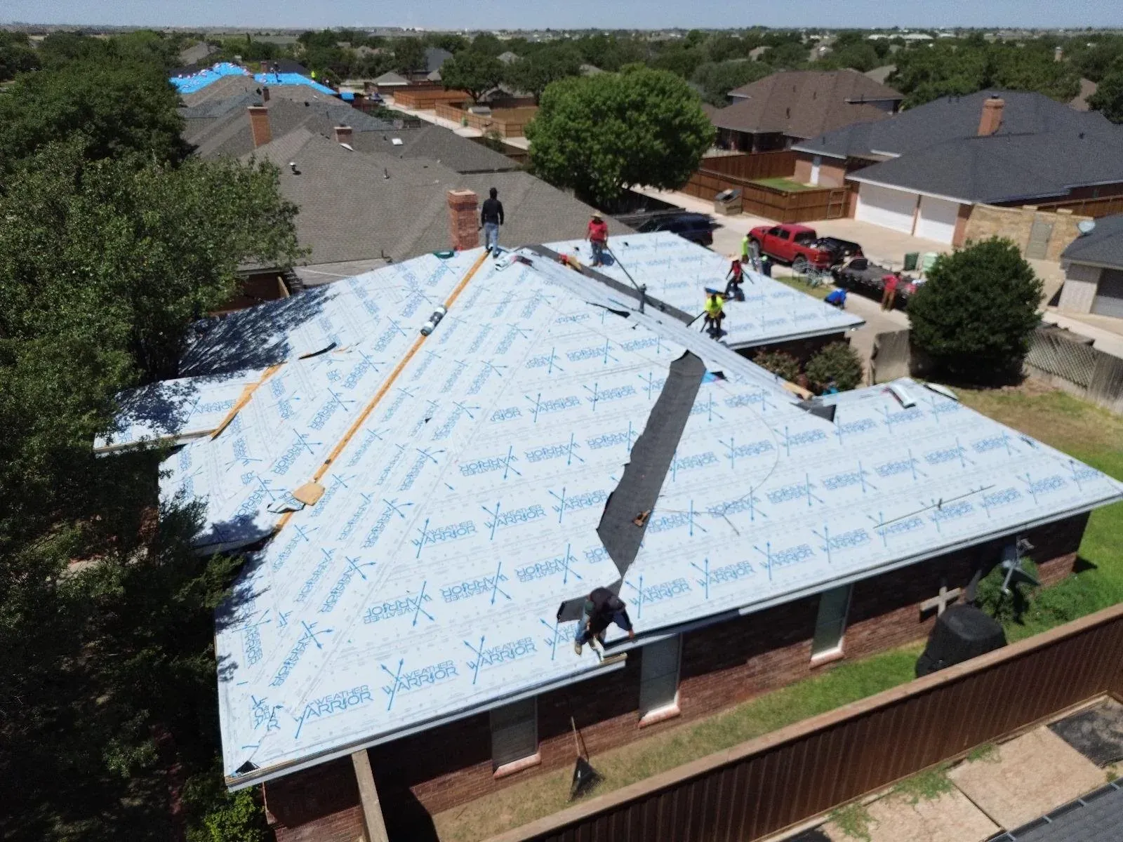Aerial view of roof replacement underlayment and crew activity